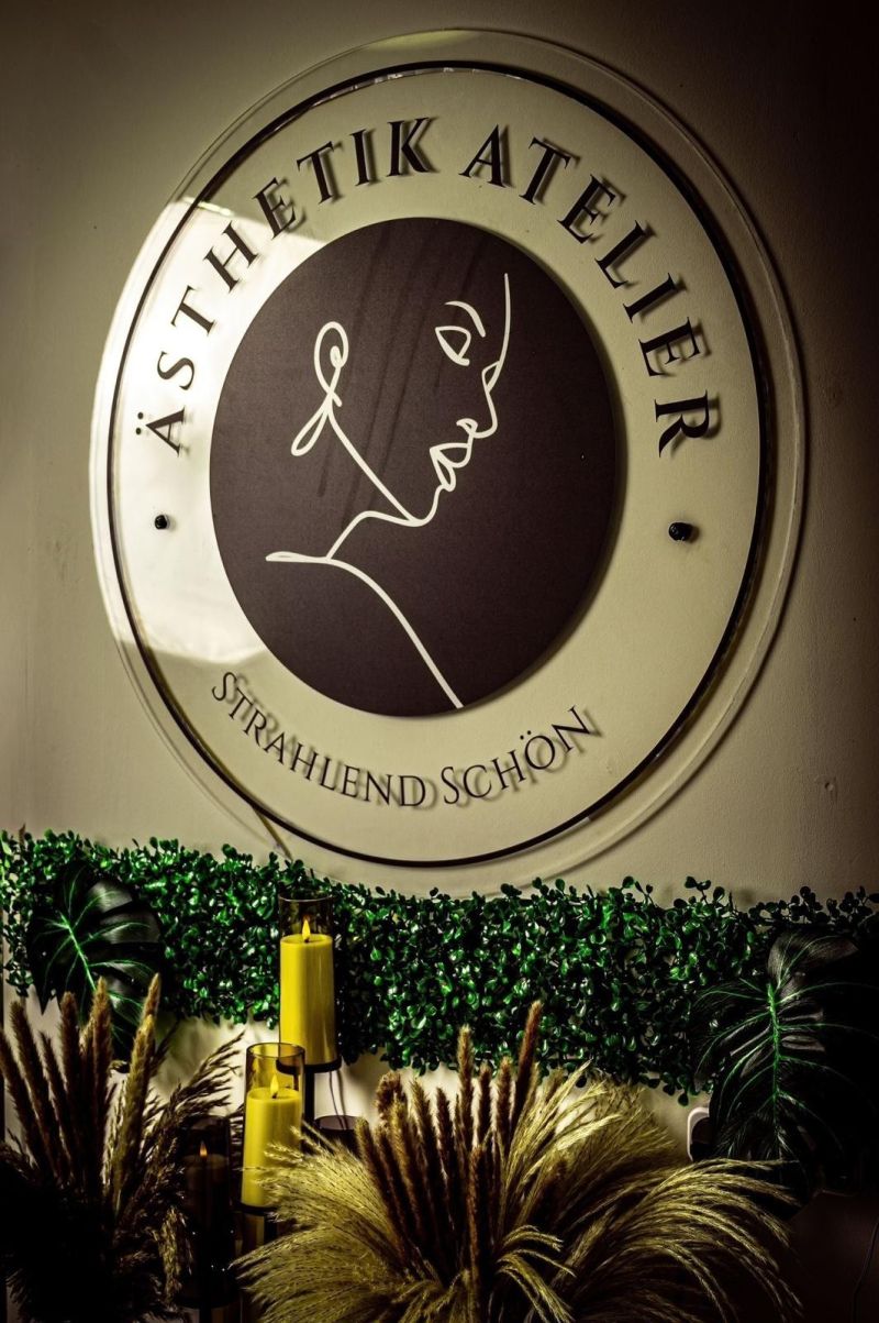 Logo-Wand des &Auml;sthetik Ateliers mit Pflanzen