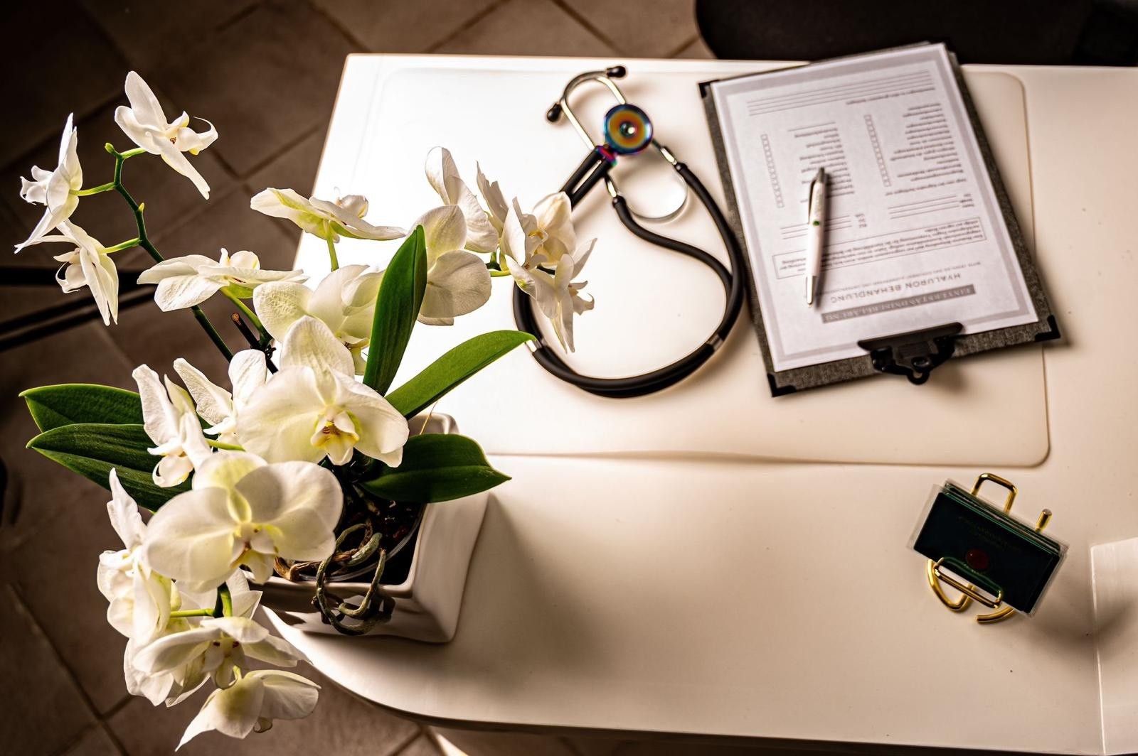 Wei&szlig;e Orchidee, Stethoskop und Klemmbrett auf einem Tisch